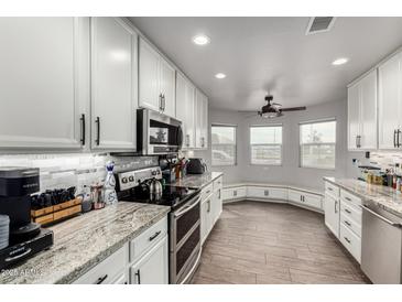 Modern kitchen with white cabinets, granite countertops, stainless steel appliances, and wood-look floors at 8576 W Mclellan Rd, Glendale, AZ 85305