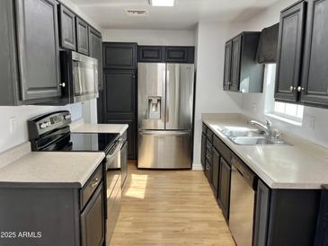 Well-lit kitchen featuring stainless steel appliances, dark cabinetry, and light countertops at 11613 N 21St Ave, Phoenix, AZ 85029