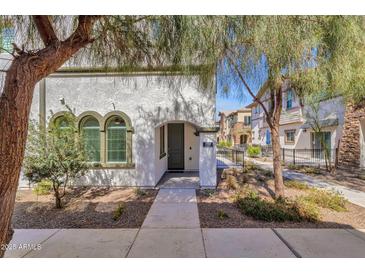 Inviting exterior view of a stucco home featuring an arched entryway, xeriscape landscaping and well-manicured trees at 2765 S Cavalier Dr # 102, Gilbert, AZ 85295