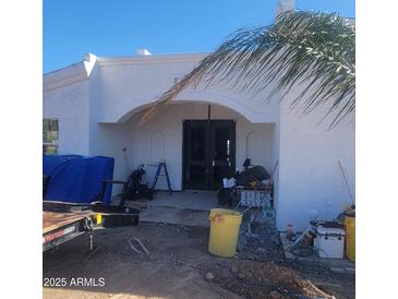 Inviting front entrance with an arched porch, stucco walls and double doors needs some TLC at 317 W Frontier St, Apache Junction, AZ 85120