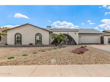 Charming home exterior with arched entry, desert landscaping, and attached two-car garage at 5129 W Echo Ln, Glendale, AZ 85302