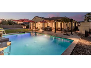 Lush backyard featuring a sparkling pool, outdoor kitchen, dining area, and sport court, perfect for entertaining at 7589 W Firebird Dr, Glendale, AZ 85308