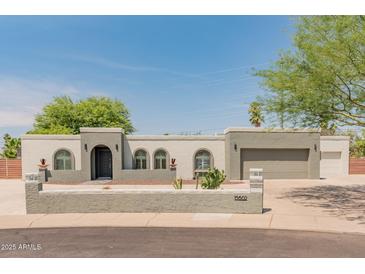 Charming single-story home with stucco facade, arched windows, desert landscaping, and a two-car garage at 15602 N 56Th Pl, Scottsdale, AZ 85254