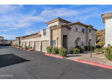 A beautiful two-story apartment exterior featuring individual garages, desert landscaping, and a neutral color palette at 3236 E Chandler Blvd # 2057, Phoenix, AZ 85048