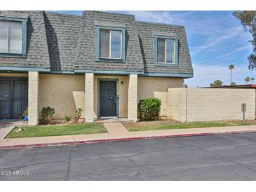 Charming townhouse featuring a gray roof, tan siding, and a secure front door at 8130 N 32Nd Dr, Phoenix, AZ 85051