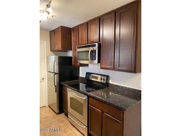 Traditional kitchen with stainless steel microwave, range, dark cabinets, and black countertops at 14145 N 92Nd St # 2004, Scottsdale, AZ 85260