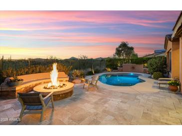 Inviting backyard oasis with a stone fire pit and pristine pool, perfect for outdoor entertaining and relaxation at 30110 N 129Th Gln, Peoria, AZ 85383