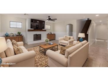 Cozy living room with a fireplace, wainscoting, tile floors, and neutral decor at 12056 W Melinda Ln, Sun City, AZ 85373