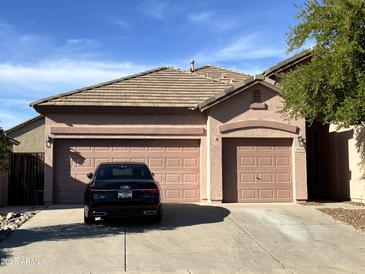 Home exterior showcases a three-car garage and desert landscaping in the front yard at 13542 W Port Au Prince Ln, Surprise, AZ 85379