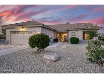 Charming single-story home with desert landscaping and a two car garage at sunset at 18137 N Plaza Ct, Surprise, AZ 85374