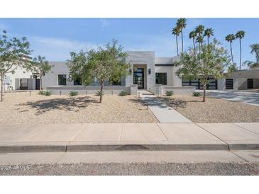 Modern home featuring a xeriscaped yard, a sleek stone accent wall, and a black framed glass front door at 7939 E Via Linda --, Scottsdale, AZ 85258