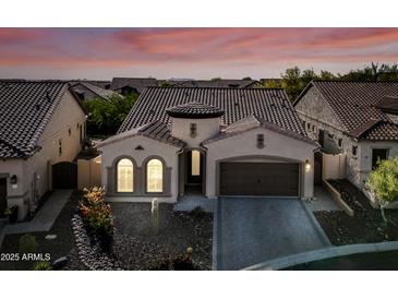 Charming single-story home boasts a tile roof, two-car garage, and beautifully landscaped front yard at sunset at 2040 N Dome Rock --, Mesa, AZ 85207