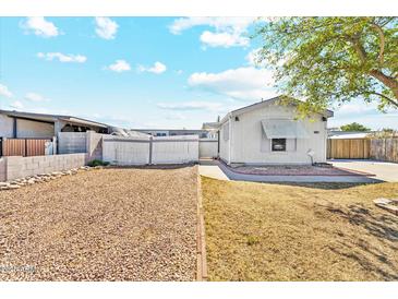 View of the side of the home with gravel yard and partial fencing at 2145 N Silverton St, Mesa, AZ 85203