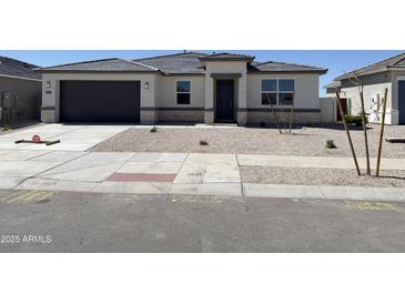 Charming single-story home featuring a gray garage door, stone accents, and a well-manicured gravel front yard at 25180 N 159Th Dr, Surprise, AZ 85387