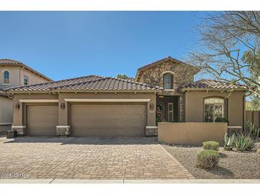 Charming home showcasing a three-car garage, stone accents and desert landscaping at 2059 W Whisper Rock Trl, Phoenix, AZ 85085