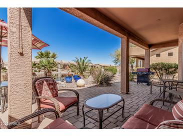 Inviting covered patio featuring comfortable seating and a serene view of a landscaped water feature at 41960 W Ellington Ln, Maricopa, AZ 85138