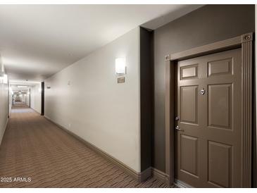 Condo hallway featuring neutral paint, carpet, and a door with decorative trim, creating a welcoming entrance at 14000 N 94Th St # 3094, Scottsdale, AZ 85260