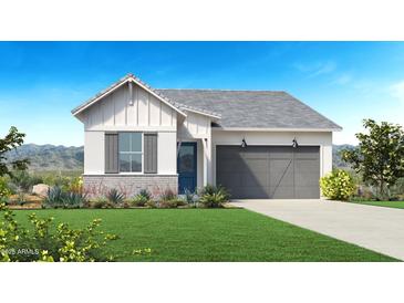 Charming single-story home with a well-manicured lawn, a gray garage door, and a blue front door at 18052 W Bighorn Ave, Goodyear, AZ 85338