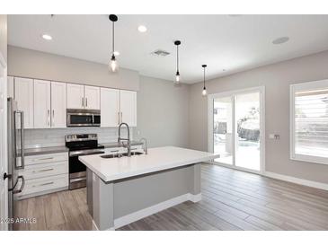 Modern kitchen features white cabinets, an island, and stainless steel appliances at 7741 E Journey Ln, Scottsdale, AZ 85255