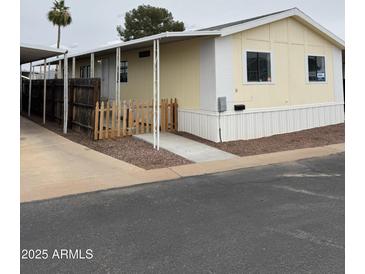 Charming single-story home featuring a covered carport and a cute picket fence at 8427 W Glendale Ave # 31, Glendale, AZ 85305