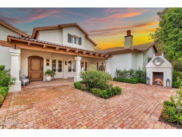 Inviting home exterior features a brick driveway, manicured landscaping, and a cozy outdoor fireplace, perfect for evening gatherings at 12 E Oakwood Hills Dr, Chandler, AZ 85248