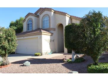 Inviting two-story stucco home featuring a two car garage, red rock landscaping and manicured bushes at 1417 W Lake Mirage Ct, Gilbert, AZ 85233