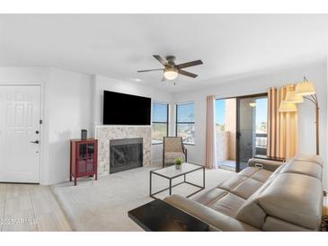 Bright living room featuring a tile fireplace, ceiling fan, sliding glass doors to balcony, and comfortable seating at 14645 N Fountain Hills N Blvd # 215, Fountain Hills, AZ 85268