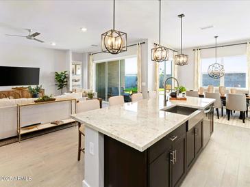 Bright, open kitchen featuring a large island with granite countertops and modern pendant lighting at 17633 W Pierson St, Goodyear, AZ 85395