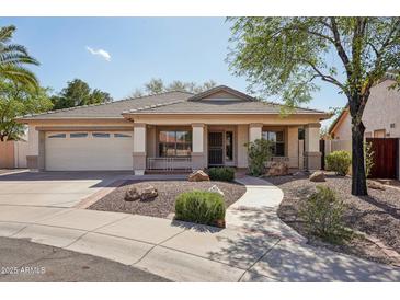 Charming single-story home features a tile roof, landscaped front yard, and inviting covered porch with stone accents at 6659 W Oraibi Dr, Glendale, AZ 85308