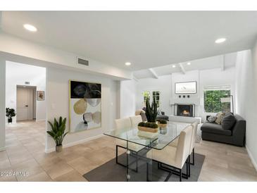 Bright living room featuring fireplace, clerestory windows, and a glass dining table near comfortable seating at 7245 E Buena Terra Way, Scottsdale, AZ 85250