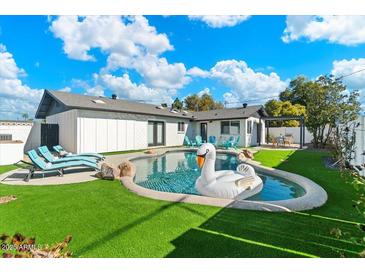 Inviting backyard featuring a pool, lounge chairs, and lush green lawn, perfect for outdoor relaxation at 8213 E Fairmount Ave, Scottsdale, AZ 85251
