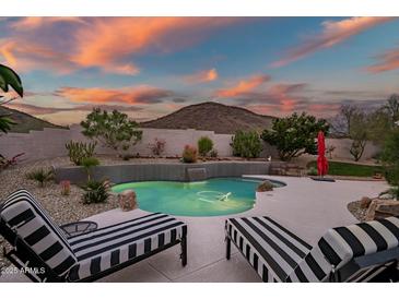 Beautiful backyard pool with a small waterfall feature, desert landscaping, and lounge chairs at 22043 N 59Th Dr, Glendale, AZ 85310