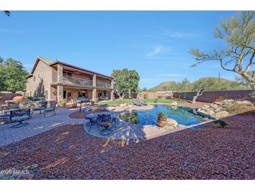 Expansive backyard featuring a pool, outdoor seating, lawn, mature trees, and a two-story house at 25767 N 67Th Dr, Peoria, AZ 85383