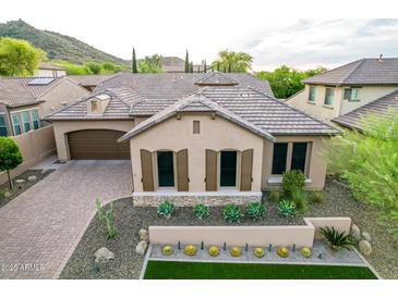 Beautiful home featuring desert landscaping, shutters, tile roof, and a brick paved driveway leading to the garage at 28834 N 68Th Ave, Peoria, AZ 85383