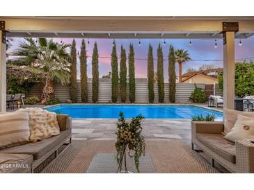 Inviting backyard features a sparkling pool, stylish patio furniture, lush landscaping, and a beautiful sunset view at 8738 E Rose Ln, Scottsdale, AZ 85250