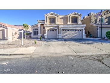 Two-story home featuring a beige stucco exterior, a three-car garage and a well-maintained front yard at 12905 W Crocus Dr, El Mirage, AZ 85335