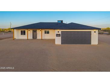 Charming single-story home featuring a gray garage door, minimalist landscaping, and stylish exterior lighting at 16567 N Slate Ln, Maricopa, AZ 85139