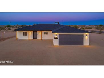 Beautiful single-story home showcasing modern exterior lighting, gray garage door, and minimalist desert landscaping at 16567 N Slate Ln, Maricopa, AZ 85139