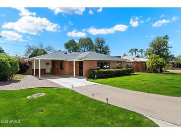 Charming brick home with well-manicured lawn and a long driveway leading to covered parking area at 1939 E Solano Dr, Phoenix, AZ 85016