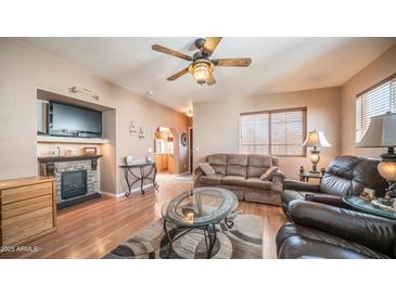 Cozy living room with a fireplace, ceiling fan, and plentiful seating space at 359 Felspar Dr, Apache Junction, AZ 85119
