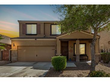 Two-story home features a large front yard, desert landscaping, attached two-car garage, and covered porch at 38085 W San Capistrano Ave, Maricopa, AZ 85138