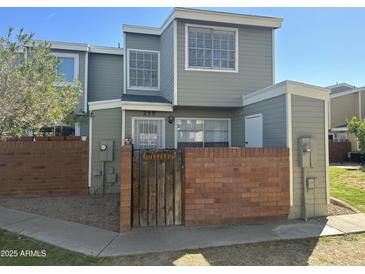 Two-story townhouse with brick fence and well-maintained front yard under a clear blue sky at 510 N Alma School Rd # 259, Mesa, AZ 85201