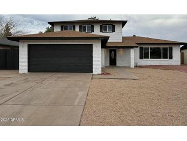 Charming two-story home featuring a dark garage door, manicured landscaping, and a cozy front porch at 5431 W Cholla St, Glendale, AZ 85304