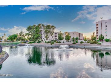 Scenic pond with fountains reflecting the residential buildings under a bright sky at 7930 E Camelback Rd # 409, Scottsdale, AZ 85251