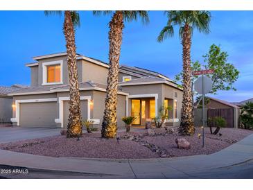 Charming two-story home featuring a well-manicured desert front yard with three palm trees and a neutral toned stucco at 15123 W Custer Ln, Surprise, AZ 85379