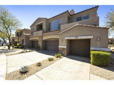 Exterior of a multi-level townhome featuring desert landscaping, and multiple car garages with stone accents at 19475 N Grayhawk Dr # 2132, Scottsdale, AZ 85255
