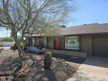 Charming single-story home featuring desert landscaping and a warm, inviting entrance with wood door at 2833 E Emile Zola Ave, Phoenix, AZ 85032