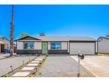 Charming single-story home features a yellow front door, a two-car garage, and low maintenance desert landscaping at 3437 E Acoma Dr, Phoenix, AZ 85032