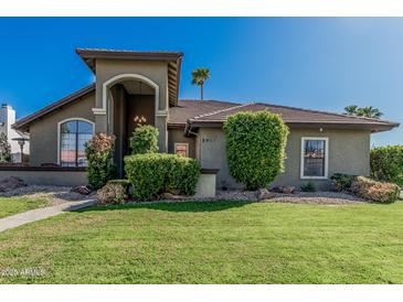 Charming single-story home with a well-manicured lawn and lush landscaping, creating inviting curb appeal at 3917 E Des Moines St, Mesa, AZ 85205