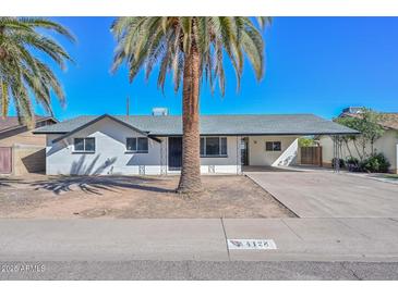 Charming single-story home featuring a white exterior, palm trees, and a covered carport at 4128 W Las Palmaritas Dr, Phoenix, AZ 85051